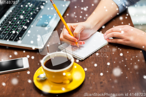 Image of woman writing to notebook with pencil