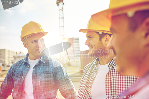 Image of group of smiling builders in hardhats outdoors