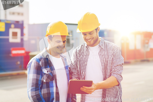 Image of smiling builders in hardhats with tablet pc