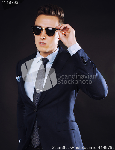 Image of young pretty business man standing on black background, modern hairstyle, talking on phone emotional