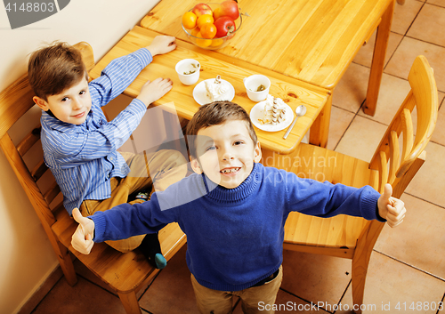 Image of little cute boys eating dessert on wooden kitchen. home interior. smiling adorable friendship together forever friends, lifestyle people concept