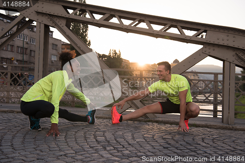 Image of jogging couple warming up and stretching in the city