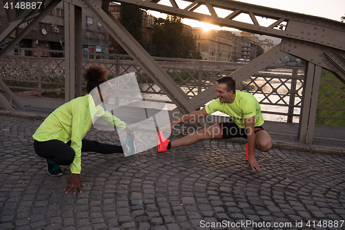 Image of jogging couple warming up and stretching in the city