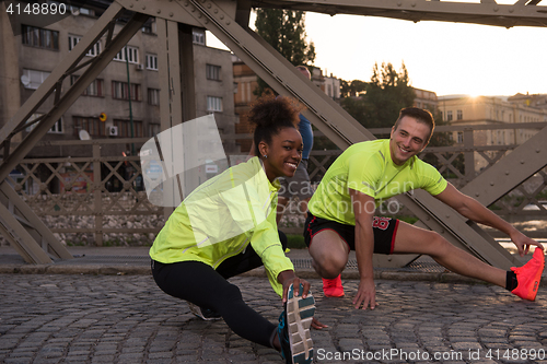 Image of jogging couple warming up and stretching in the city