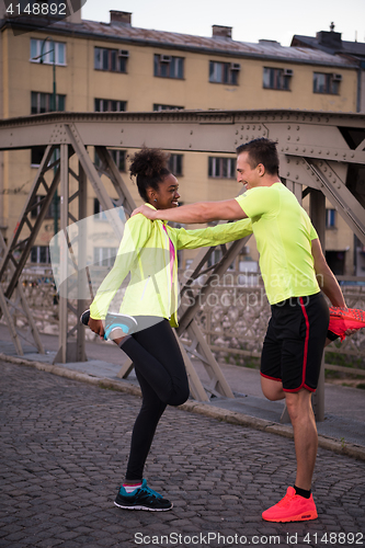 Image of jogging couple warming up and stretching in the city