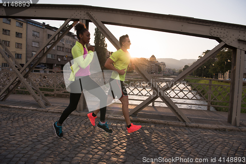 Image of young multiethnic couple jogging in the city