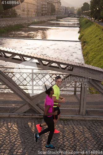 Image of young multiethnic couple jogging in the city
