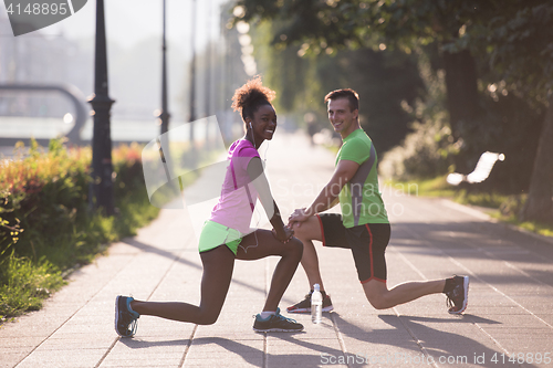 Image of jogging couple warming up and stretching in the city