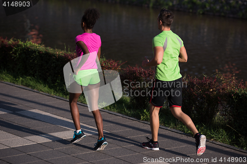 Image of young smiling multiethnic couple jogging in the city