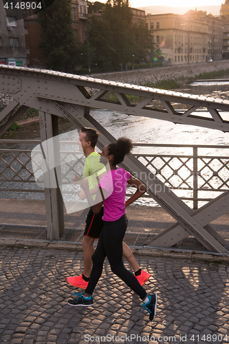 Image of young multiethnic couple jogging in the city