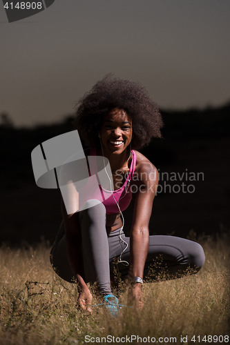 Image of black woman runner tightening shoe lace