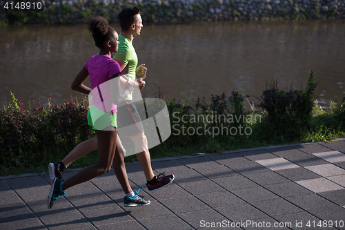 Image of young smiling multiethnic couple jogging in the city