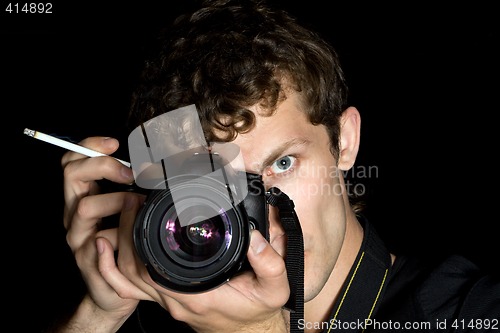 Image of The young man - photographer behind work. Isolated on a black ba