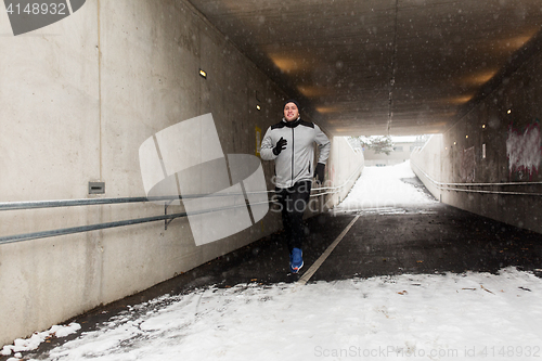 Image of happy man running along subway tunnel in winter