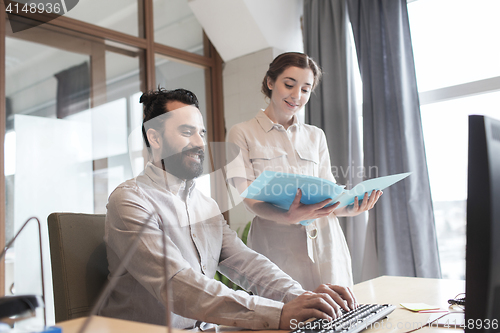 Image of happy creative team with computer in office