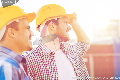 Image of group of smiling builders in hardhats outdoors