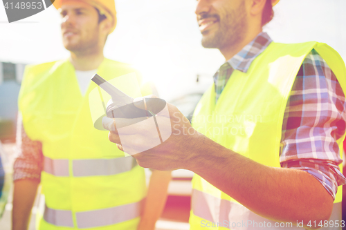 Image of close up of builders in vests with walkie talkie