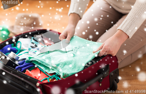 Image of close up of woman packing travel bag for vacation