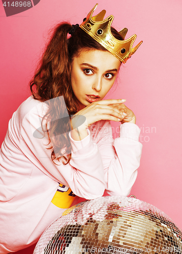 Image of young cute disco girl on pink background with disco ball and cro