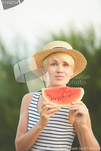 Image of Beautiful girl in straw hat eating fresh watermelon. Film camera style