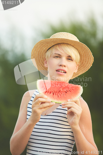 Image of Beautiful girl in straw hat eating fresh watermelon. Film camera style