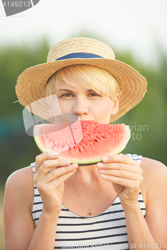 Image of Beautiful girl in straw hat eating fresh watermelon. Film camera style