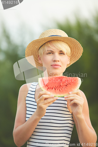 Image of Beautiful girl in straw hat eating fresh watermelon. Film camera style