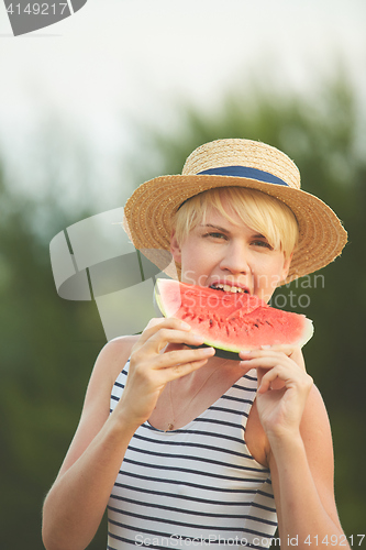 Image of Beautiful girl in straw hat eating fresh watermelon. Film camera style