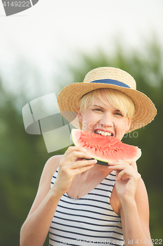 Image of Beautiful girl in straw hat eating fresh watermelon. Film camera style