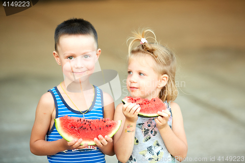 Image of Young girl and boy eating watermelon