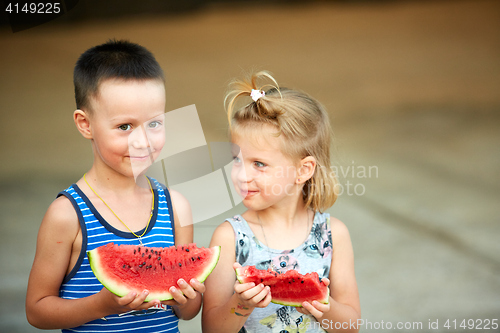 Image of Young girl and boy eating watermelon