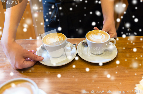 Image of close up of hands with latte art in coffee cup