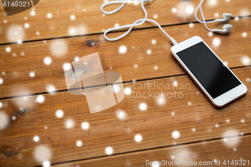 Image of close up of blank smartphone and earphones on wood