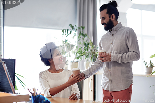 Image of happy man bringing coffee to woman in office