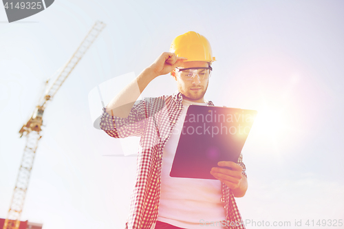 Image of builder in hardhat with clipboard outdoors