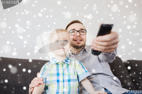 Image of father and son with remote watching tv at home