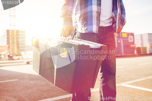 Image of close up of builder carrying toolbox outdoors