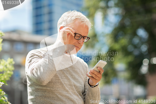 Image of senior man texting message on smartphone in city