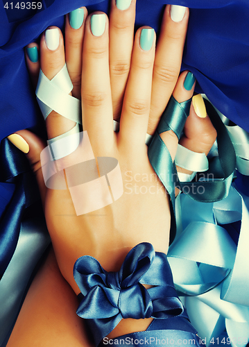 Image of blue manicure with ribbon close up as a gift