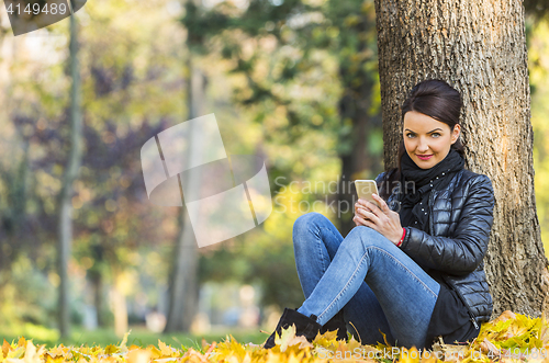 Image of Woman with a Mobile in a Forest in the Autumn