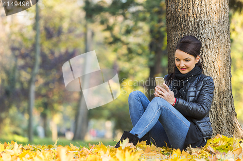 Image of Woman with a Mobile in a Forest in the Autumn