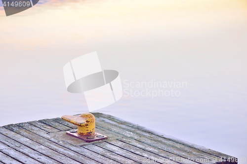 Image of Yellow bollard, or a harbor post, on a wooden pier.