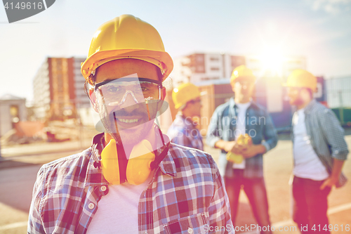 Image of smiling builder with hardhat and headphones