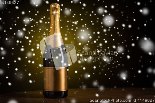 Image of bottle of champagne with golden label over snow