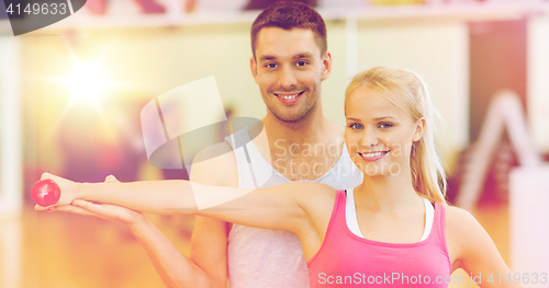 Image of male trainer with woman working out with dumbbell