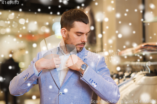 Image of young man trying jacket on in clothing store