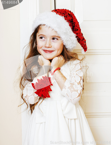 Image of little cute girl in santas red hat waiting for Christmas gifts. 