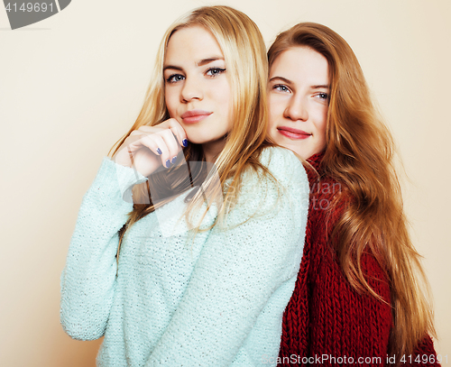 Image of Two young girlfriends in winter sweaters indoors having fun. Lif