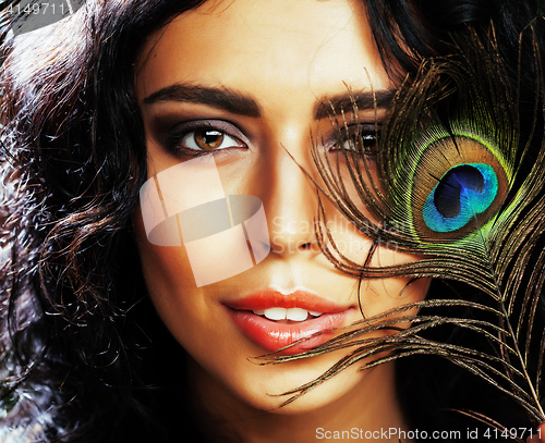 Image of young sensitive brunette woman with peacock feather eyes close up