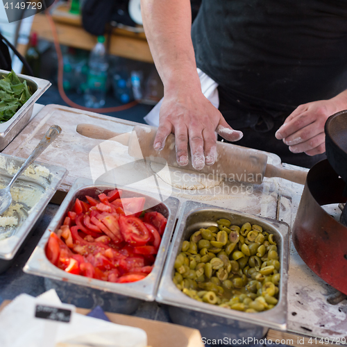 Image of Chef making pita bread for falafel roll outdoor on street stall.